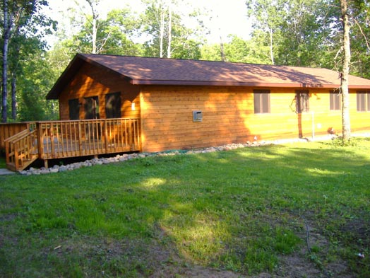 Outside View of Cabin #17 with large deck, BBQ grill and picnic table.  The deck faces North; parking is at the south of this cabin.  Ramp leads to the kitchen entry door and the spacious deck.